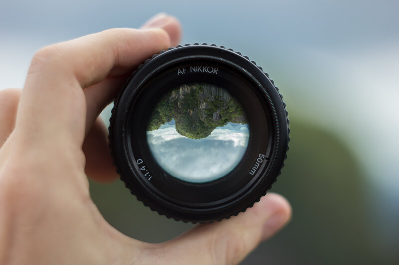 Hand Holding Camera Lens — Black, Serene