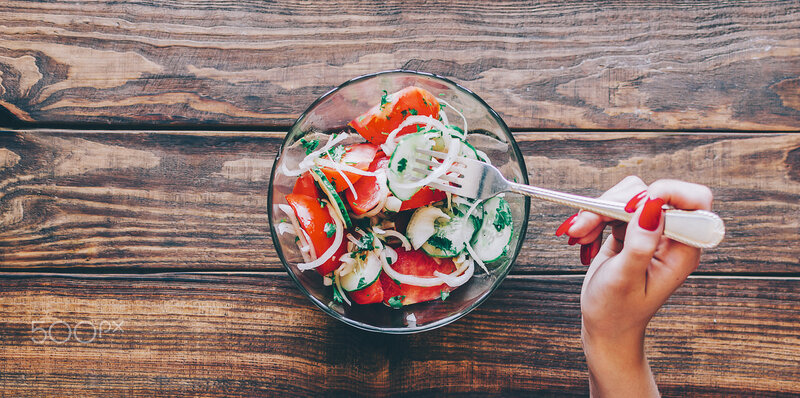 Hand Holding Fork over Salad