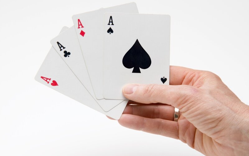 hand holding four aces