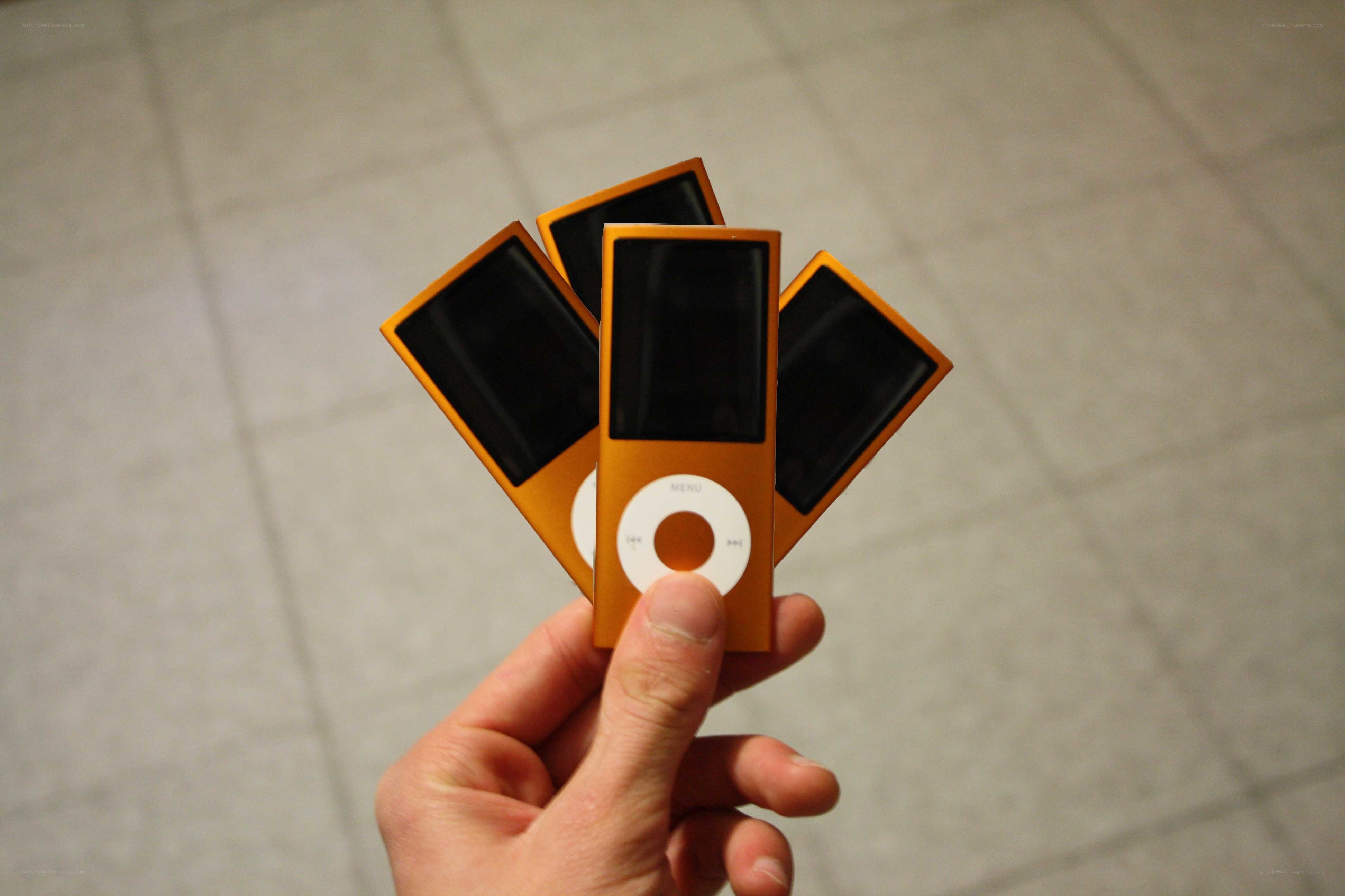 Hand holding four orange iPods