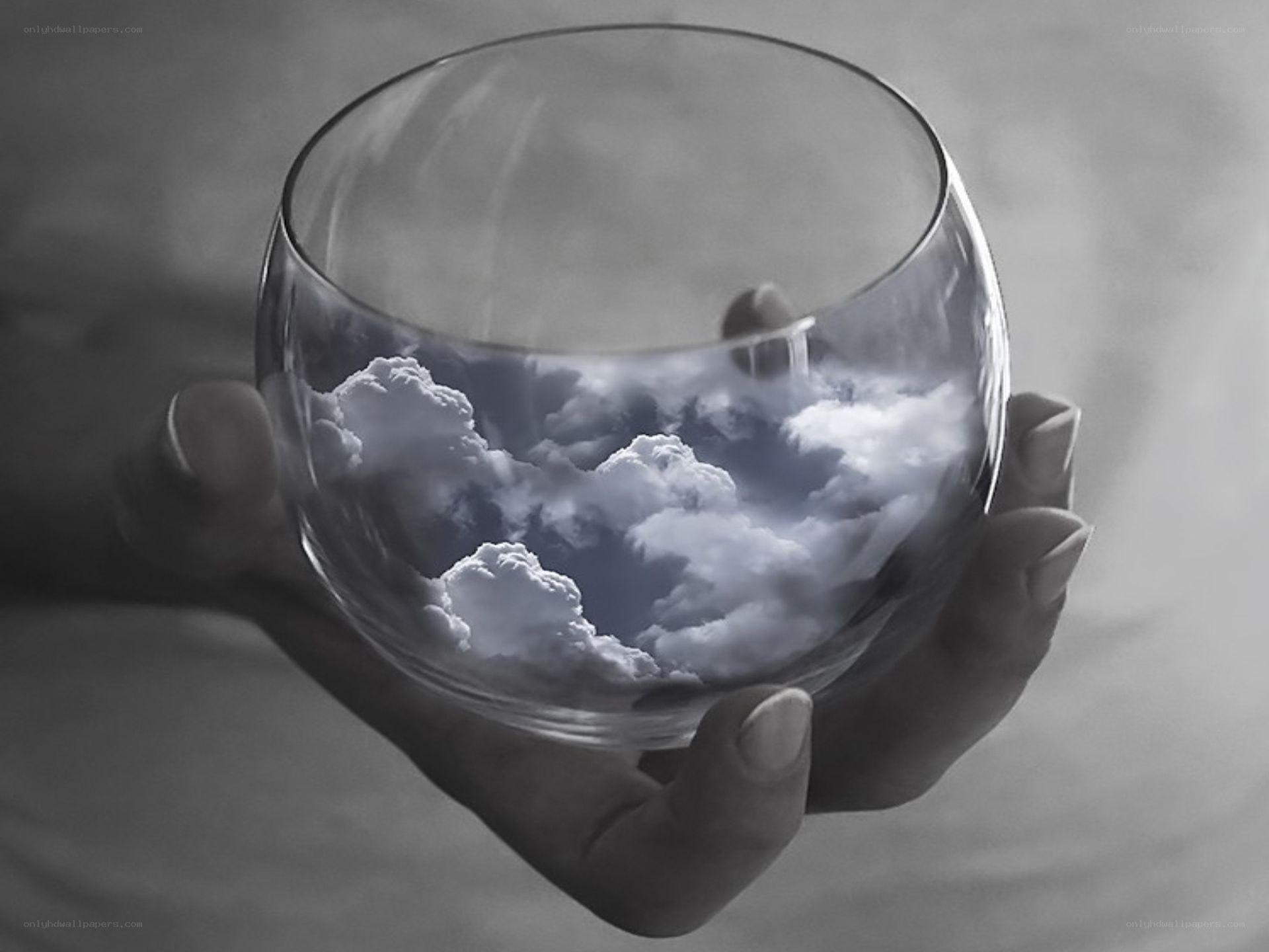 Hand holding glass with clouds
