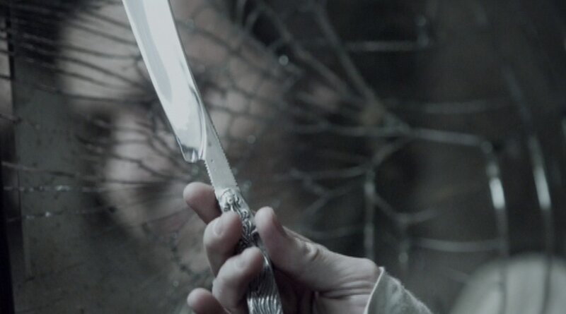 hand holding knife behind glass
