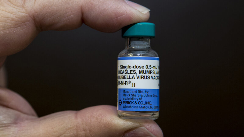 Hand holding MMR vaccine vial