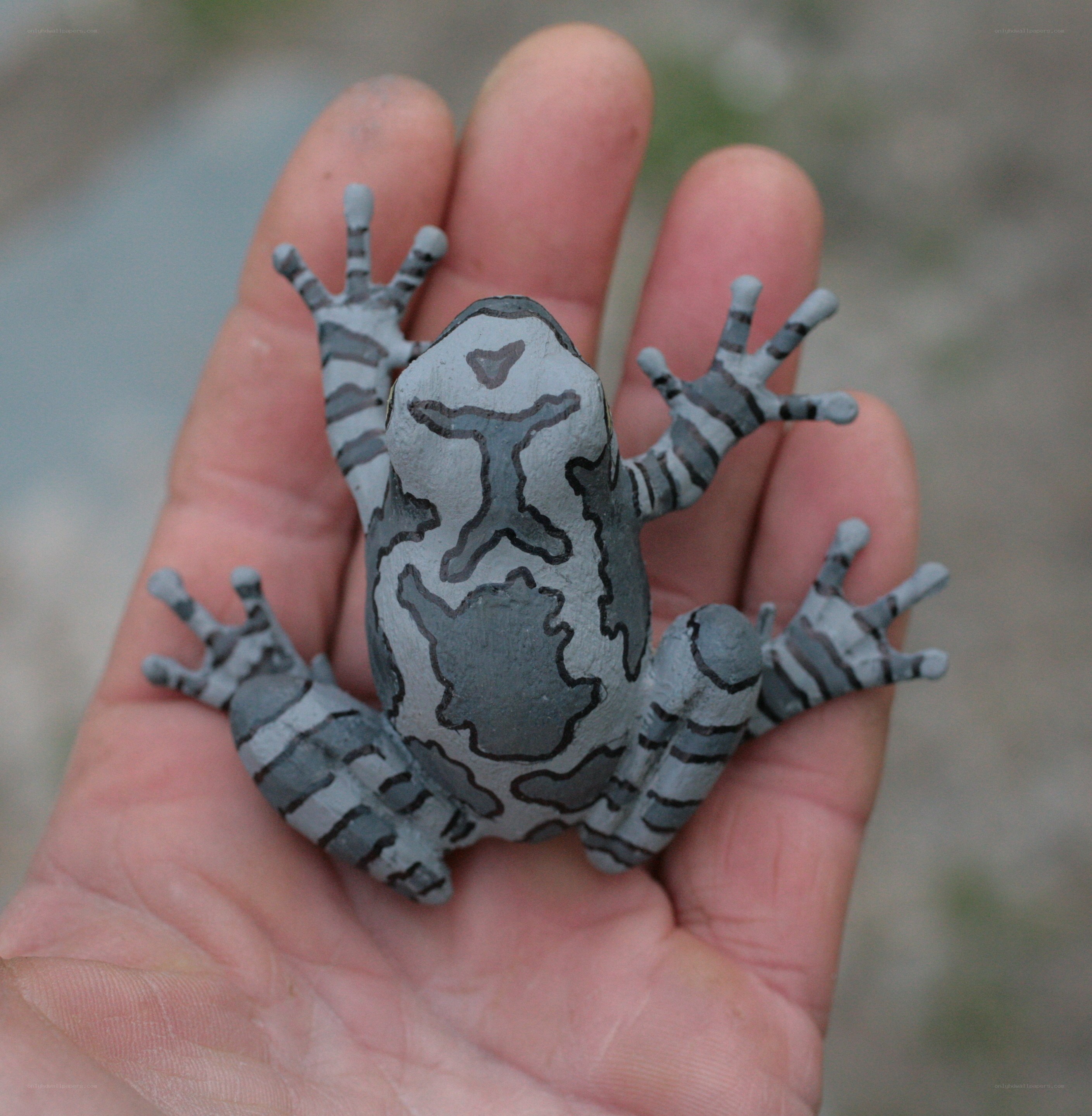 hand holding painted frog figurine