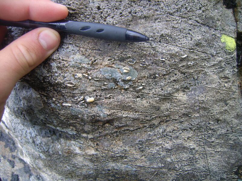 hand holding pen on rock surface