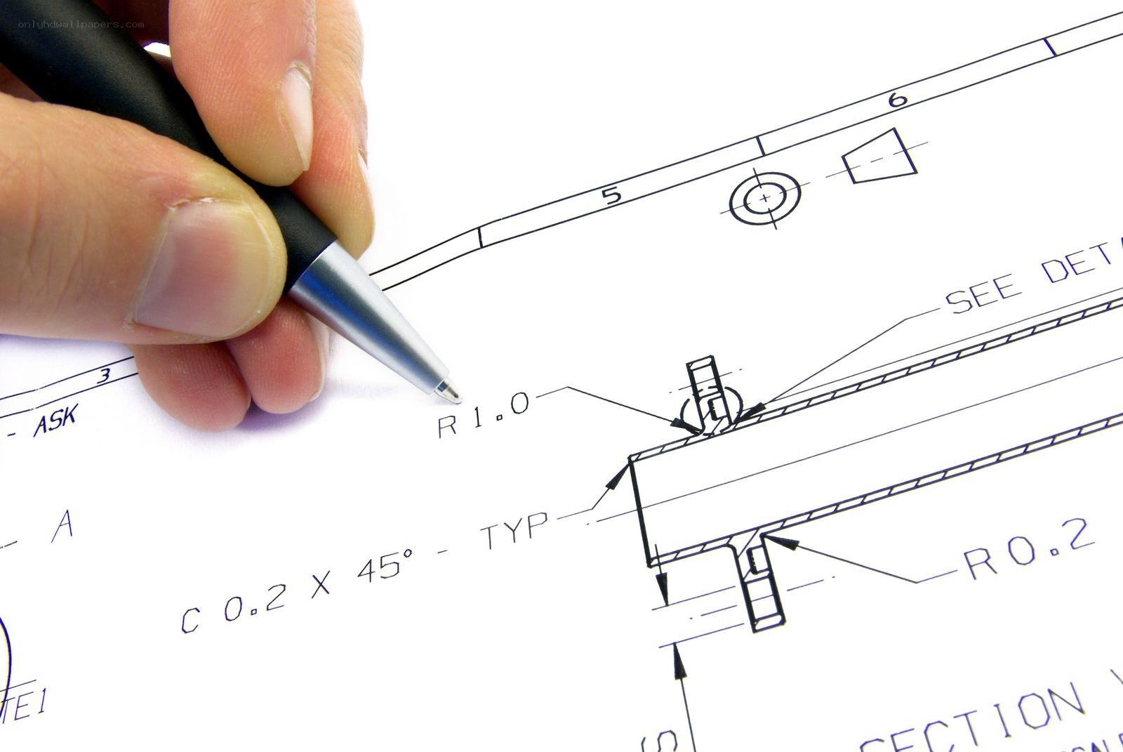 hand holding pen over blueprint