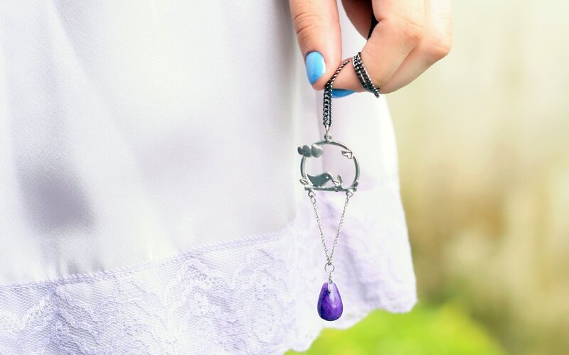 hand holding purple pendant necklace