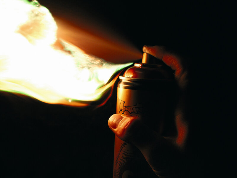 Hand holding spray can with flame