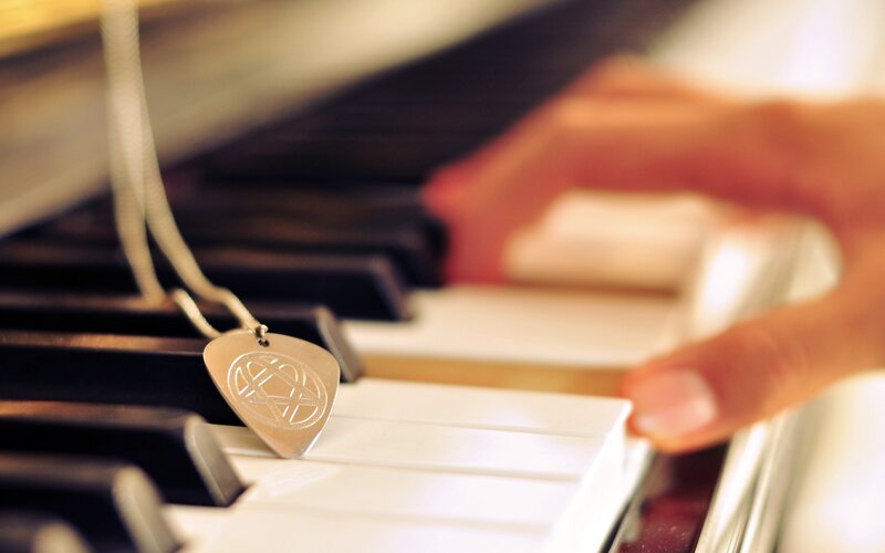 Hand on piano keys with pendant