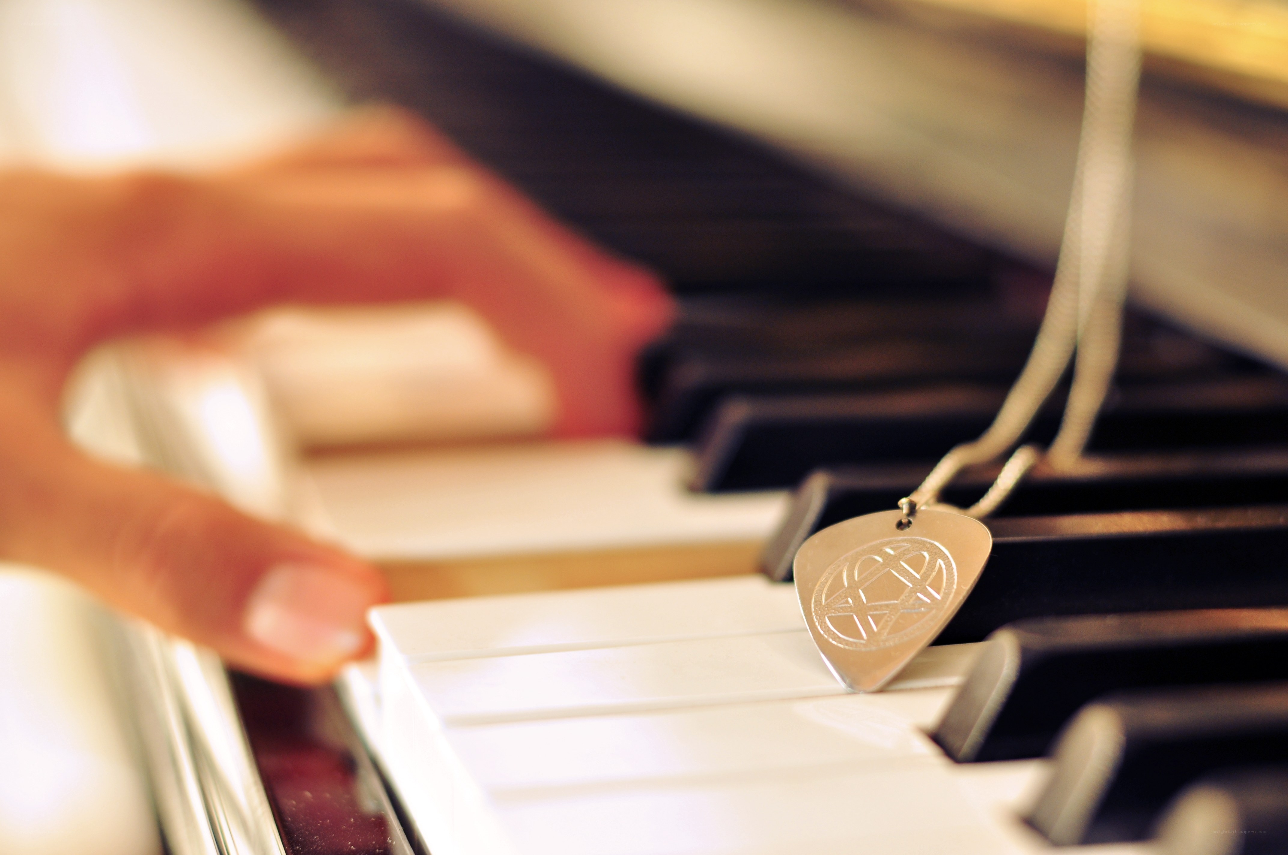 hand on piano keys with pendant