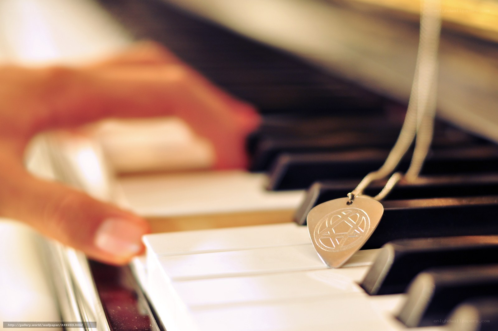 hand on piano with guitar pick pendant