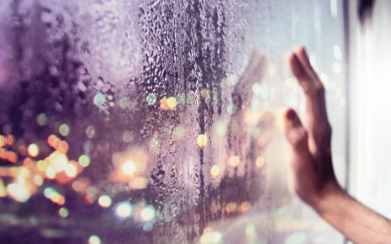hand on rainy window at night