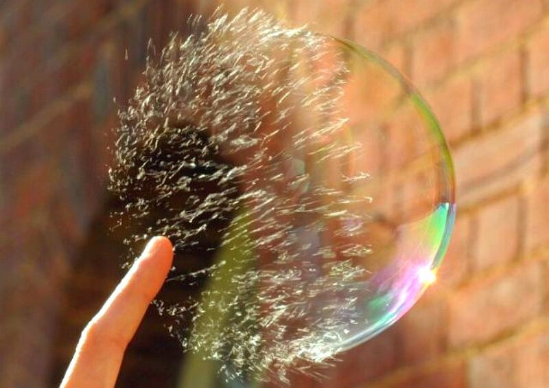hand popping a soap bubble