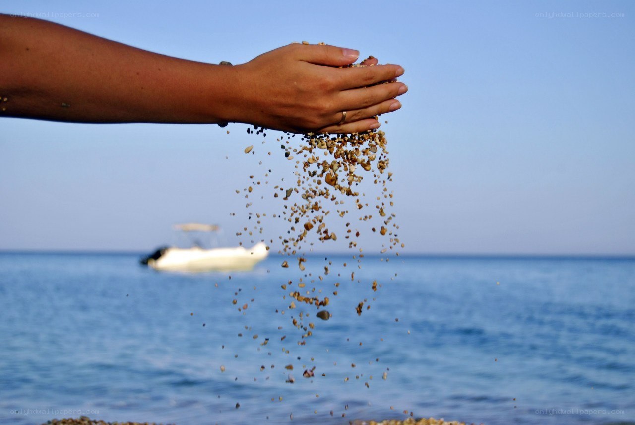 hand pouring sand on beach