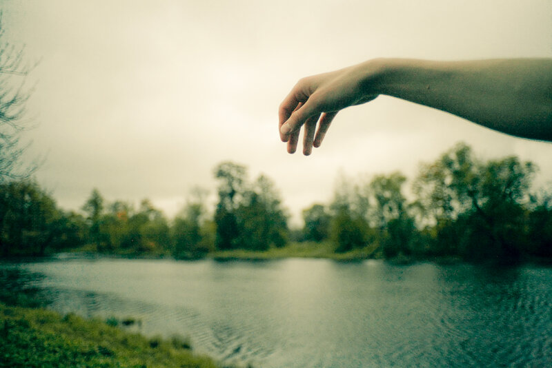 hand reaching over a lake