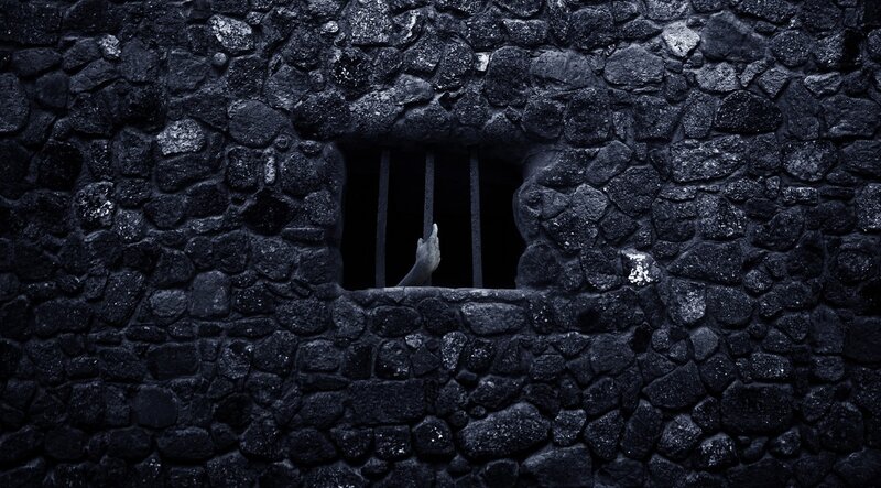 Hand reaching through prison bars