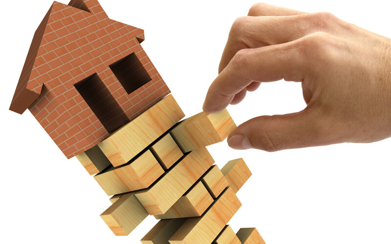 hand removing block from house structure
