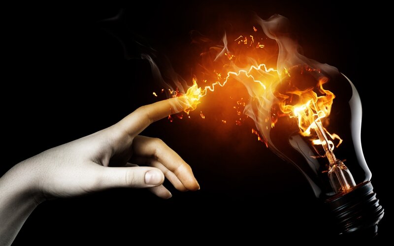 hand touching light bulb with fire