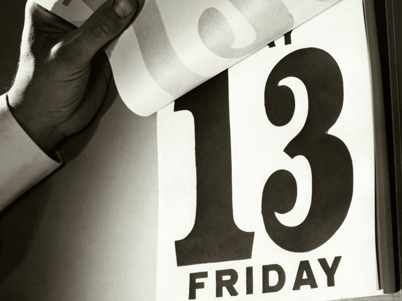 hand turning calendar page to Friday the 13th