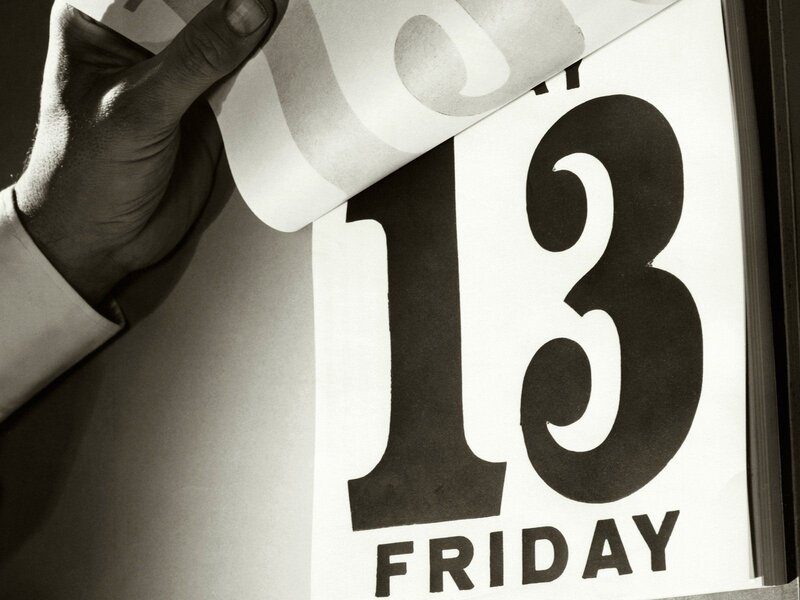 hand turning calendar page to Friday the 13th