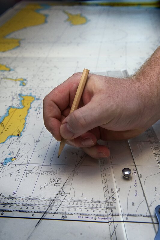 hand using pencil on nautical chart
