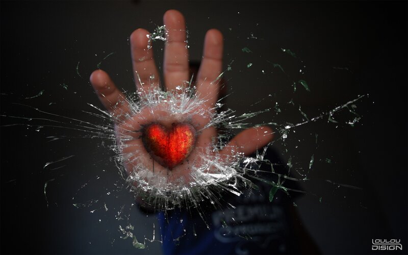 hand with heart behind broken glass