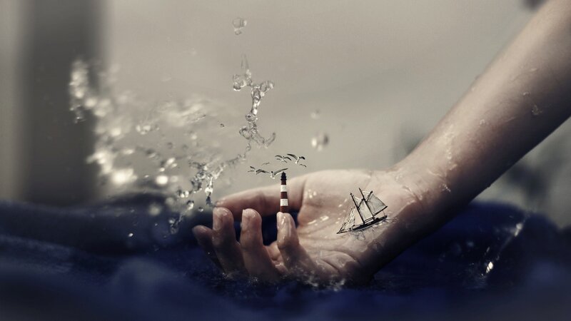 hand with miniature ship and lighthouse