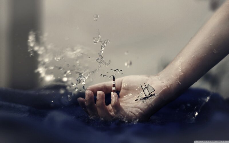 hand with miniature ship and lighthouse