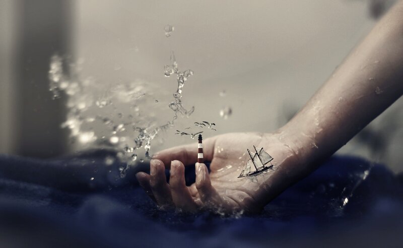 hand with miniature ship and lighthouse