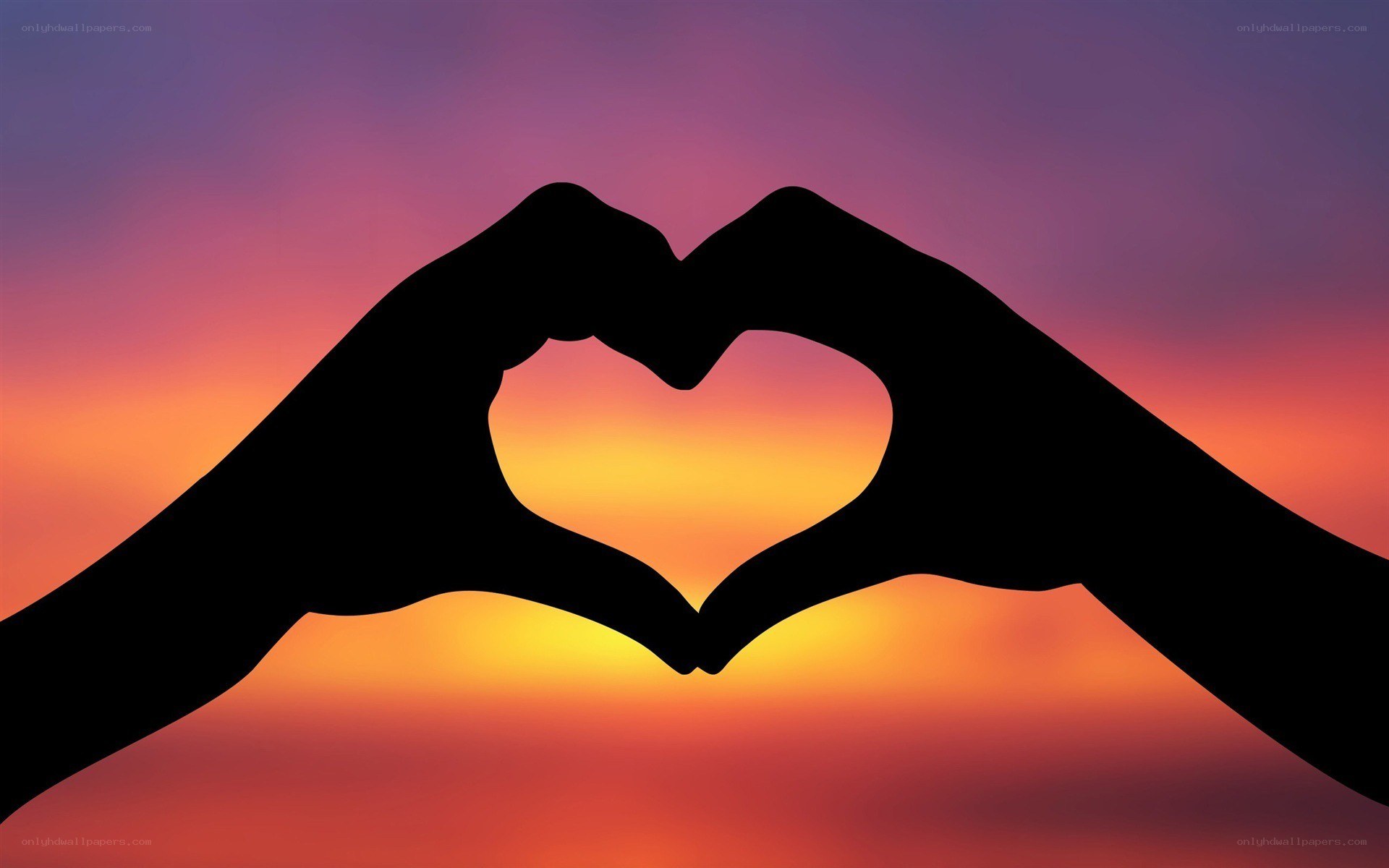 hands forming heart at sunset