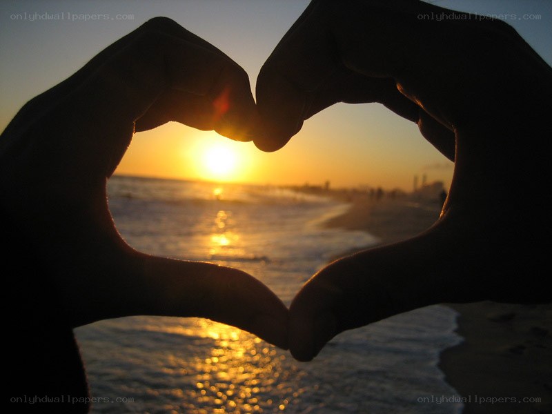 hands forming heart at sunset
