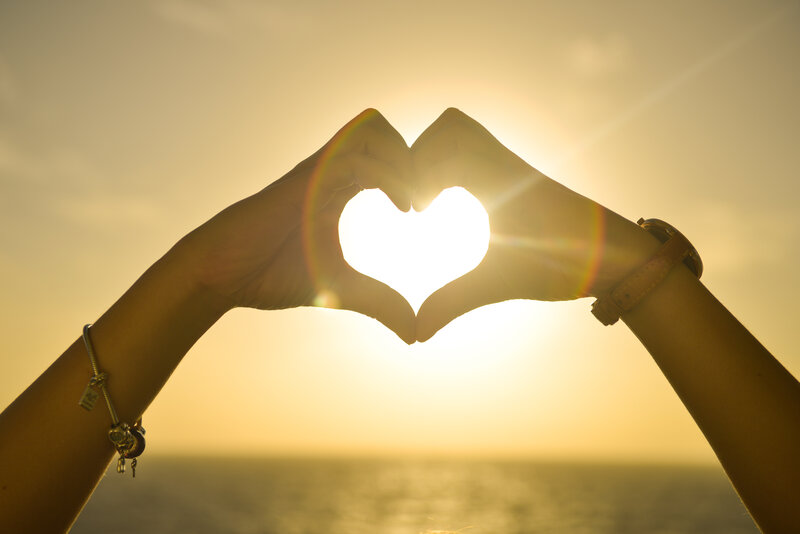 Hands forming heart at sunset