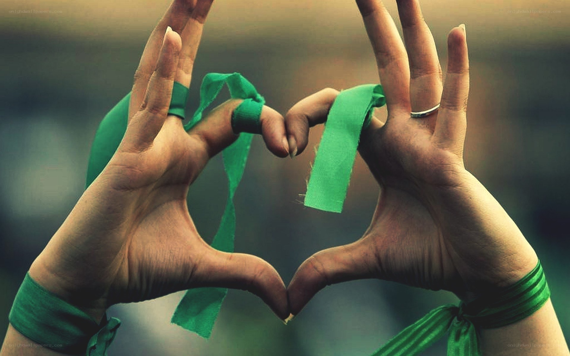 Hands forming heart with green ribbon