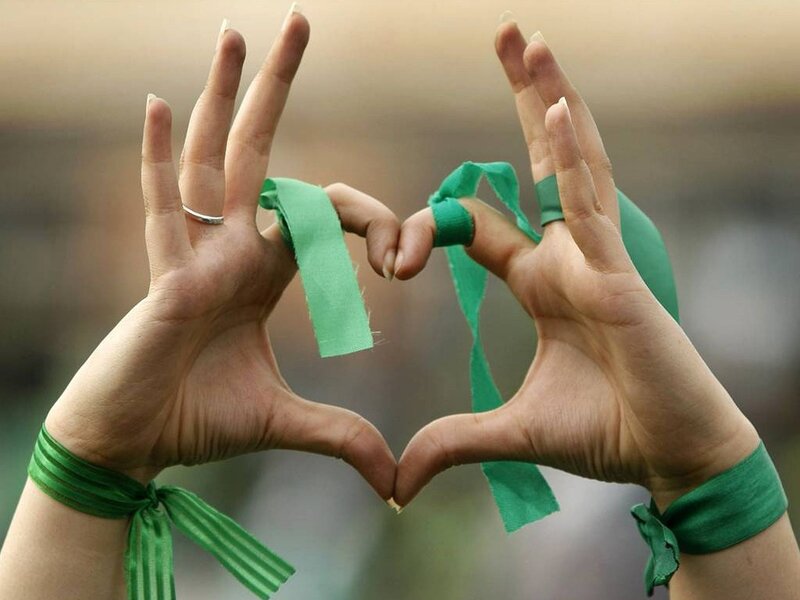 Hands forming heart with green ribbons