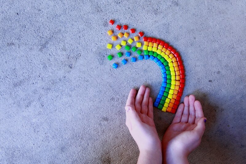 Hands holding a rainbow of candies