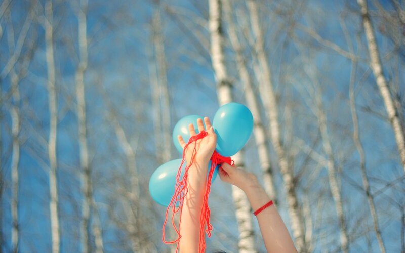 hands holding blue balloons