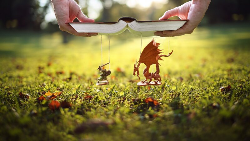 Hands Holding Book with Miniatures