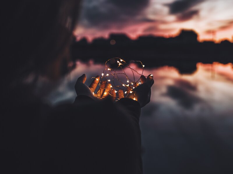 hands holding fairy lights at dusk