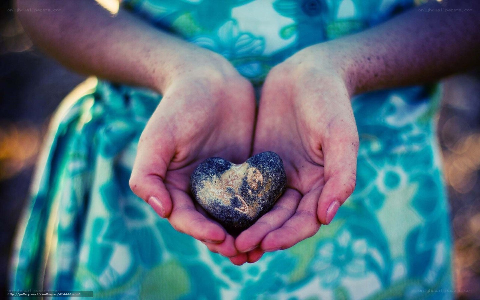 Hands holding heart-shaped stone