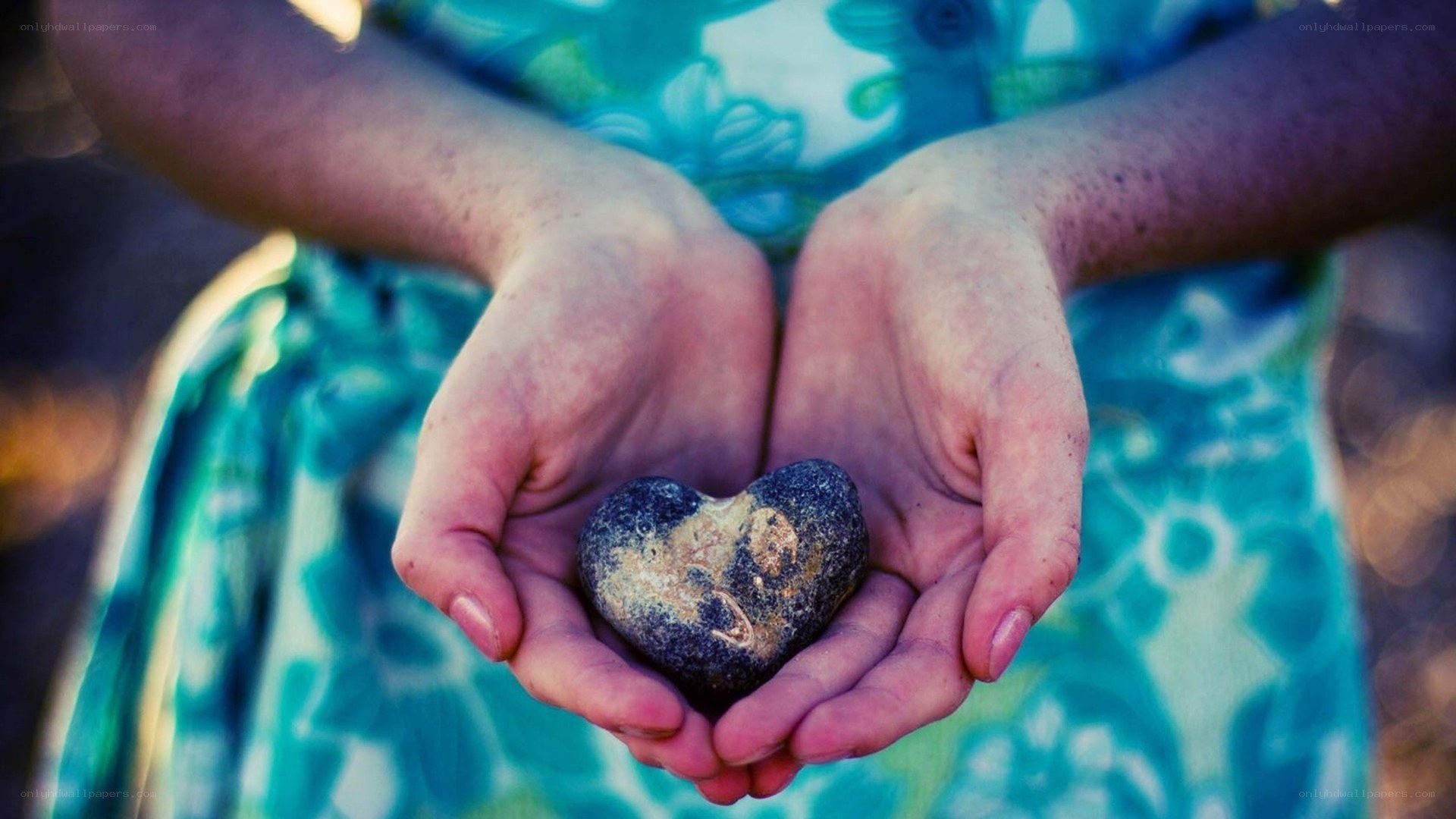 hands holding heart-shaped stone