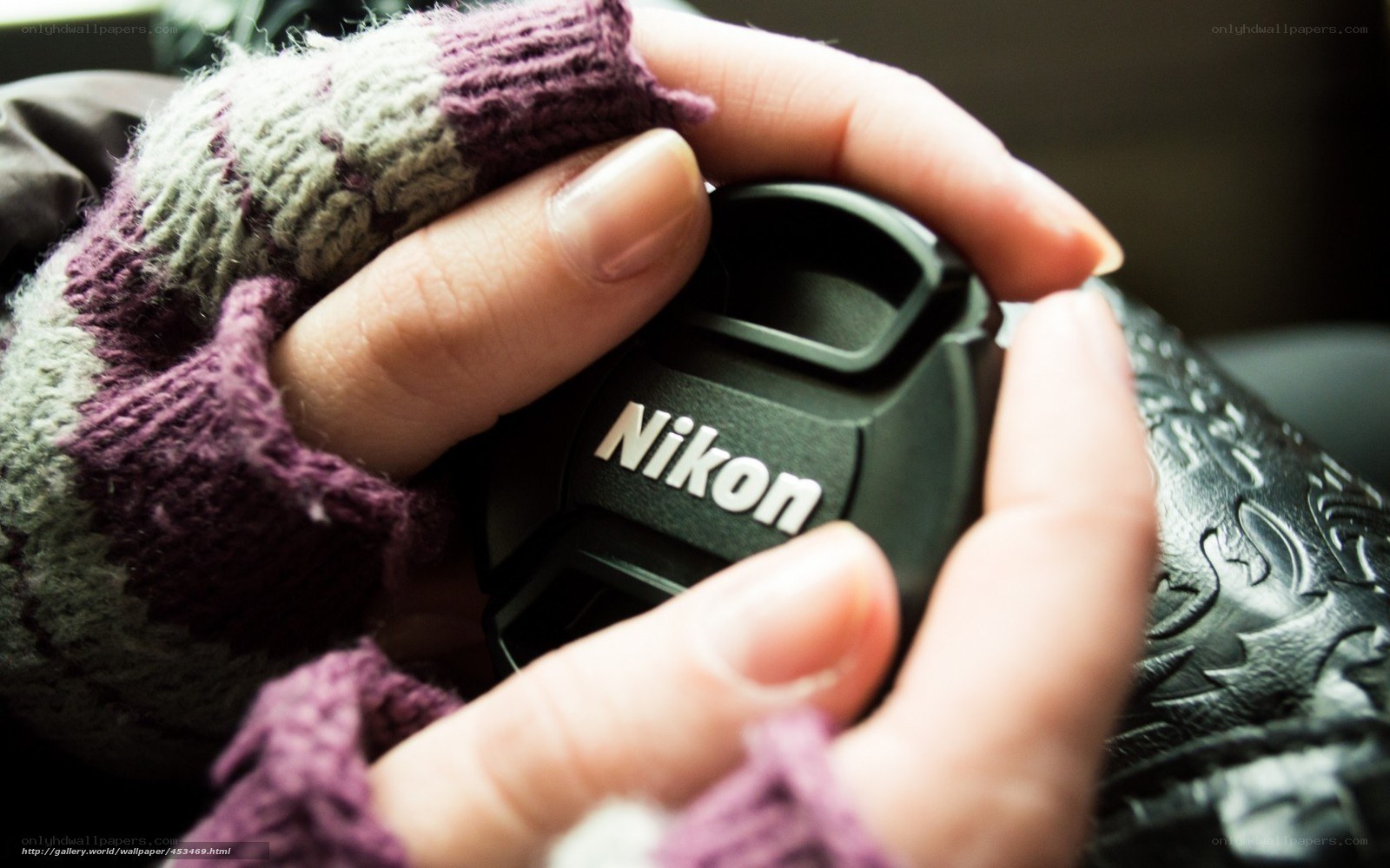 hands holding nikon lens cap