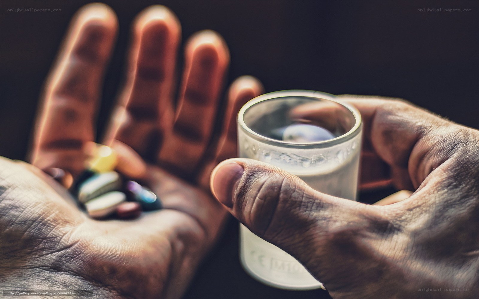 hands holding pills and glass