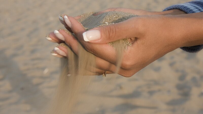 hands holding sand at beach