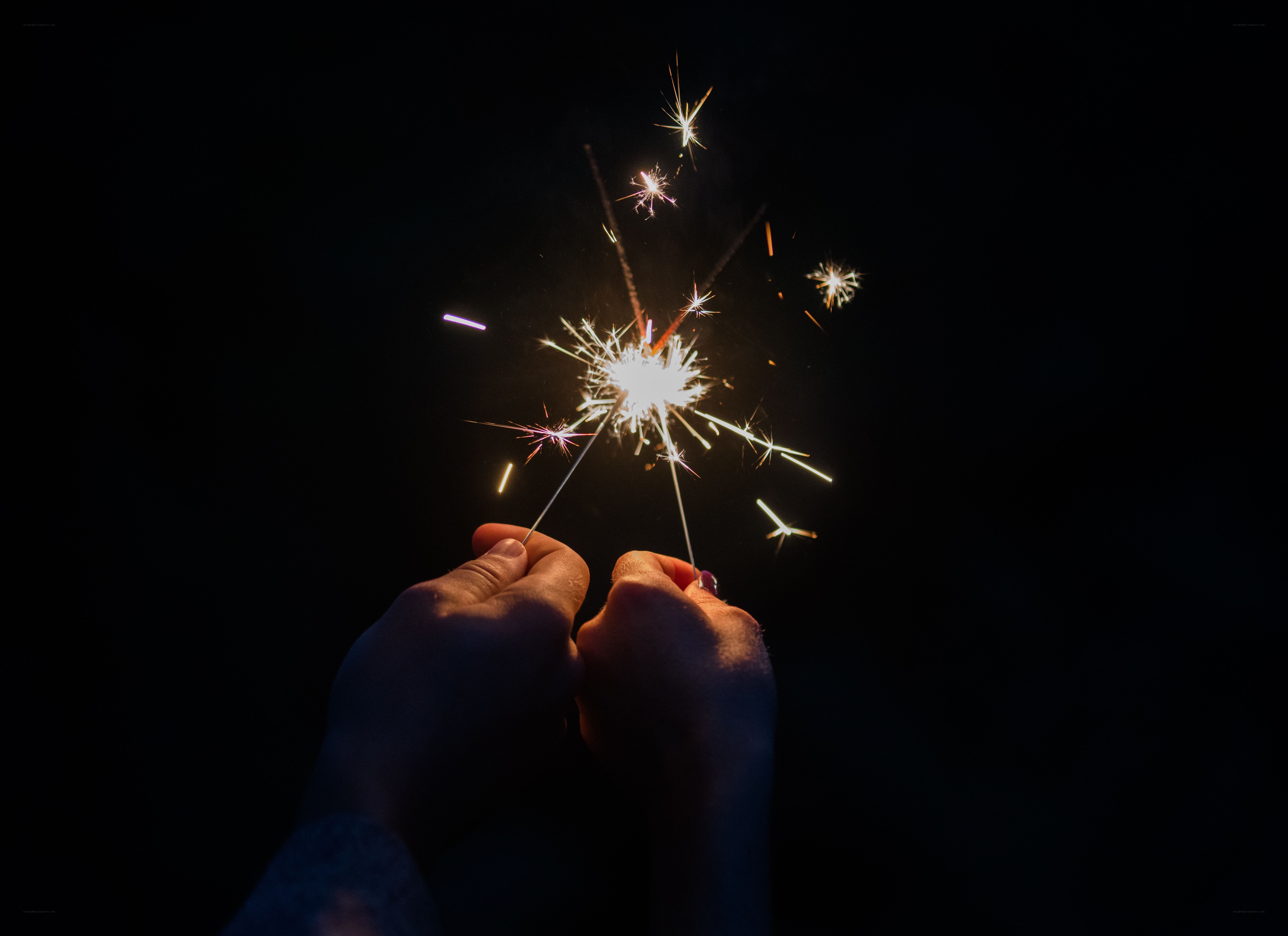 Hands holding sparklers at night