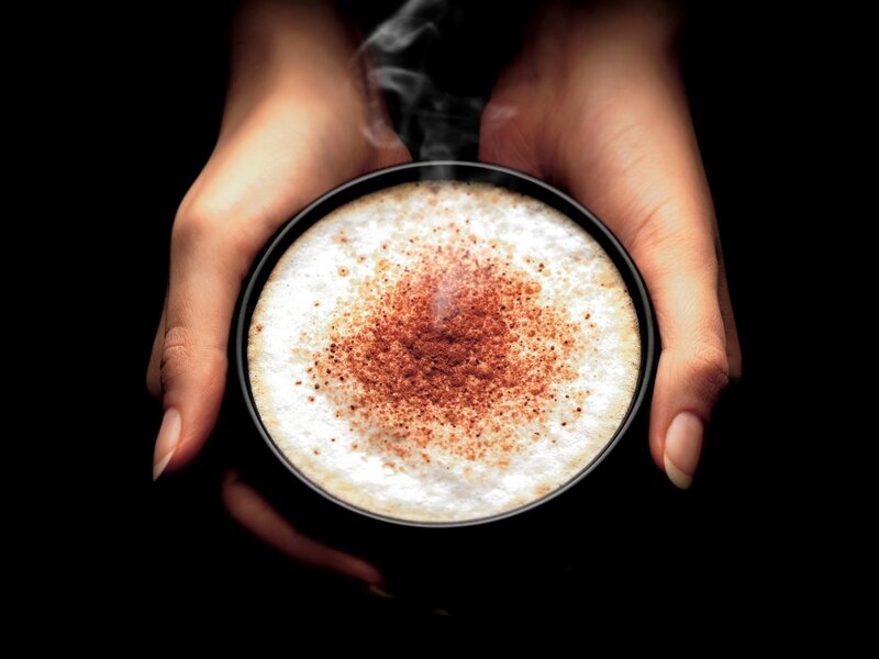 hands holding steaming coffee