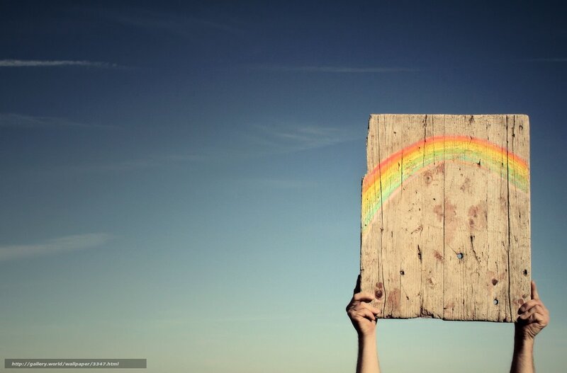 Hands holding wooden sign with rainbow