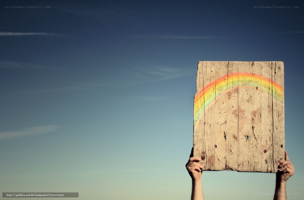 Hands holding wooden sign with rainbow