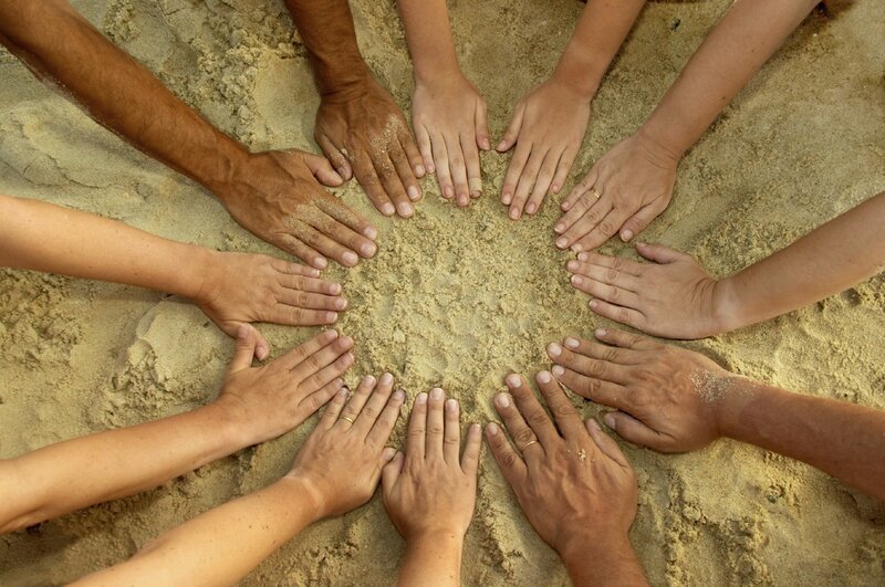 hands in a circle on sand