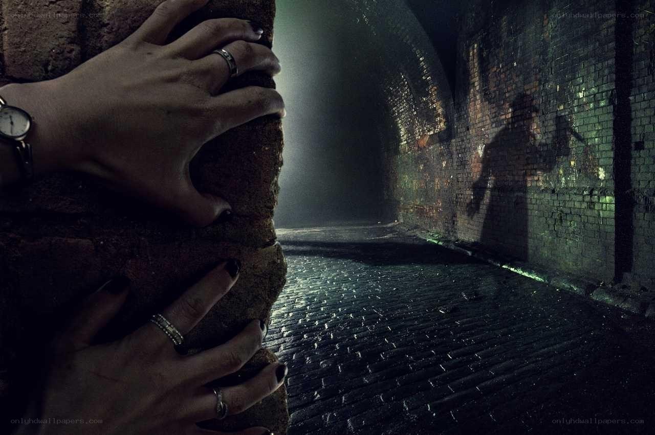 hands on brick wall in tunnel