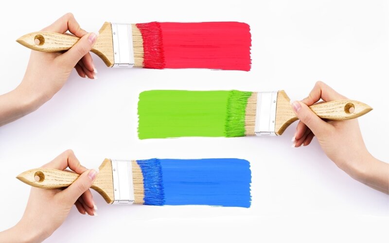 Hands painting with colorful brushes